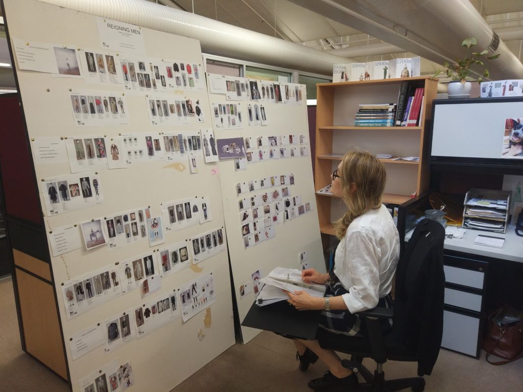 Assistant Curator Alysha Buss reviewing a folder of object research files with the brainstorm pin boards